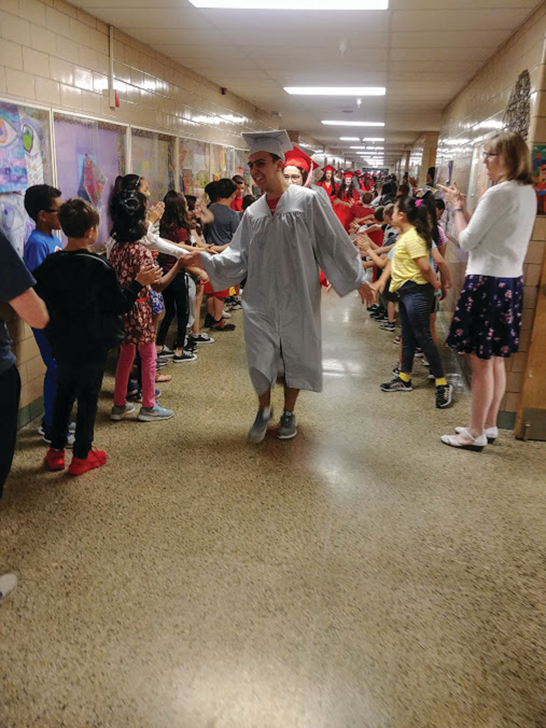 HIGH FIVES AND APPLAUSE: At Woodridge Elementary School, staff and students lined the hallways, sharing hugs, high-fives and a round of applause as the seniors walked through.